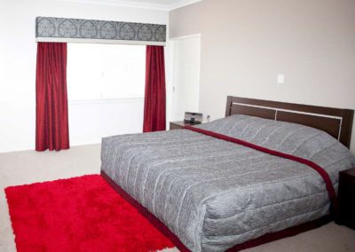 bedroom with red curtains and damask pelmet